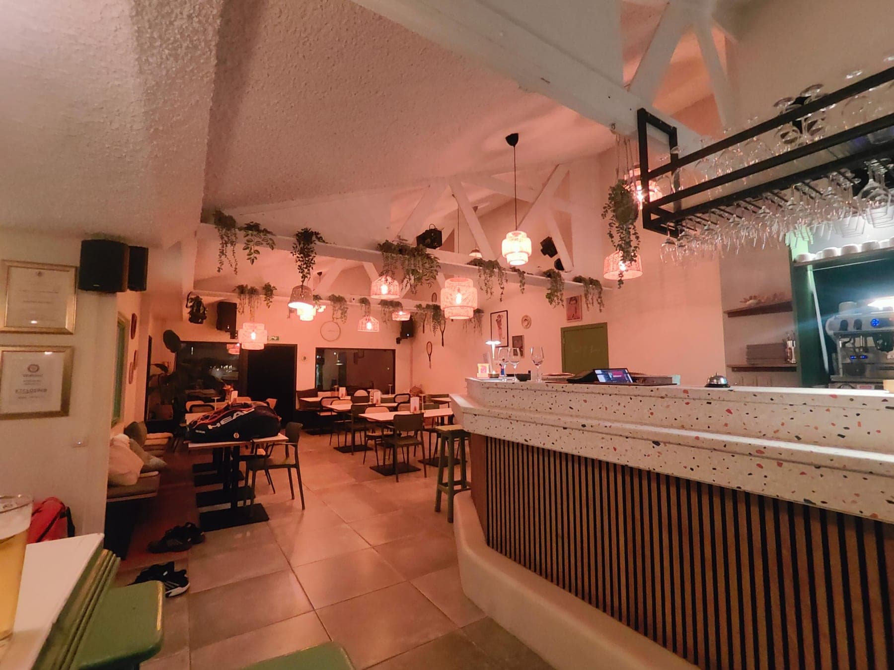 Het interieur van de bistro, met de bar, hanglampen en planten