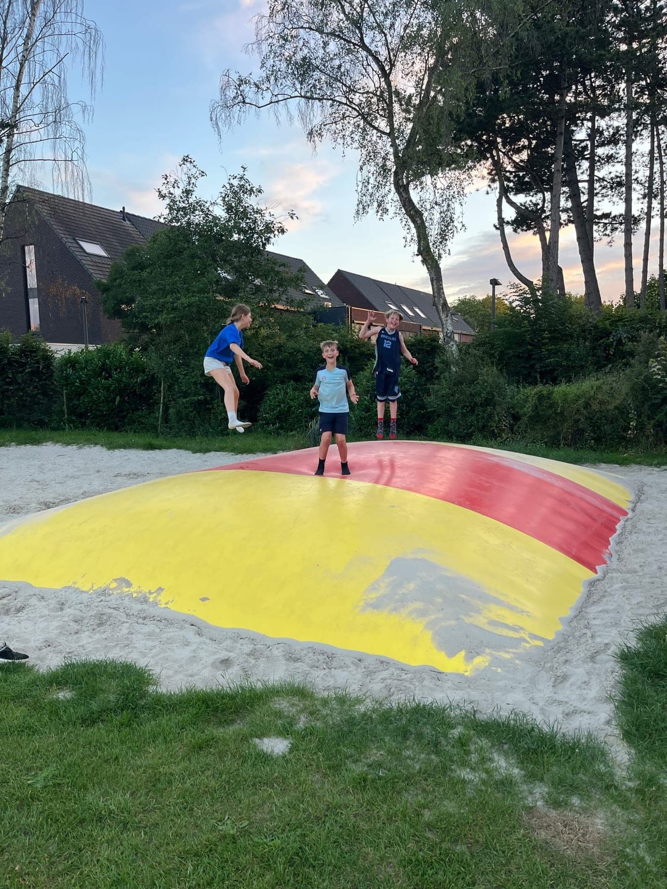 Drie kinderen springen op het springkussen naast de terreinen