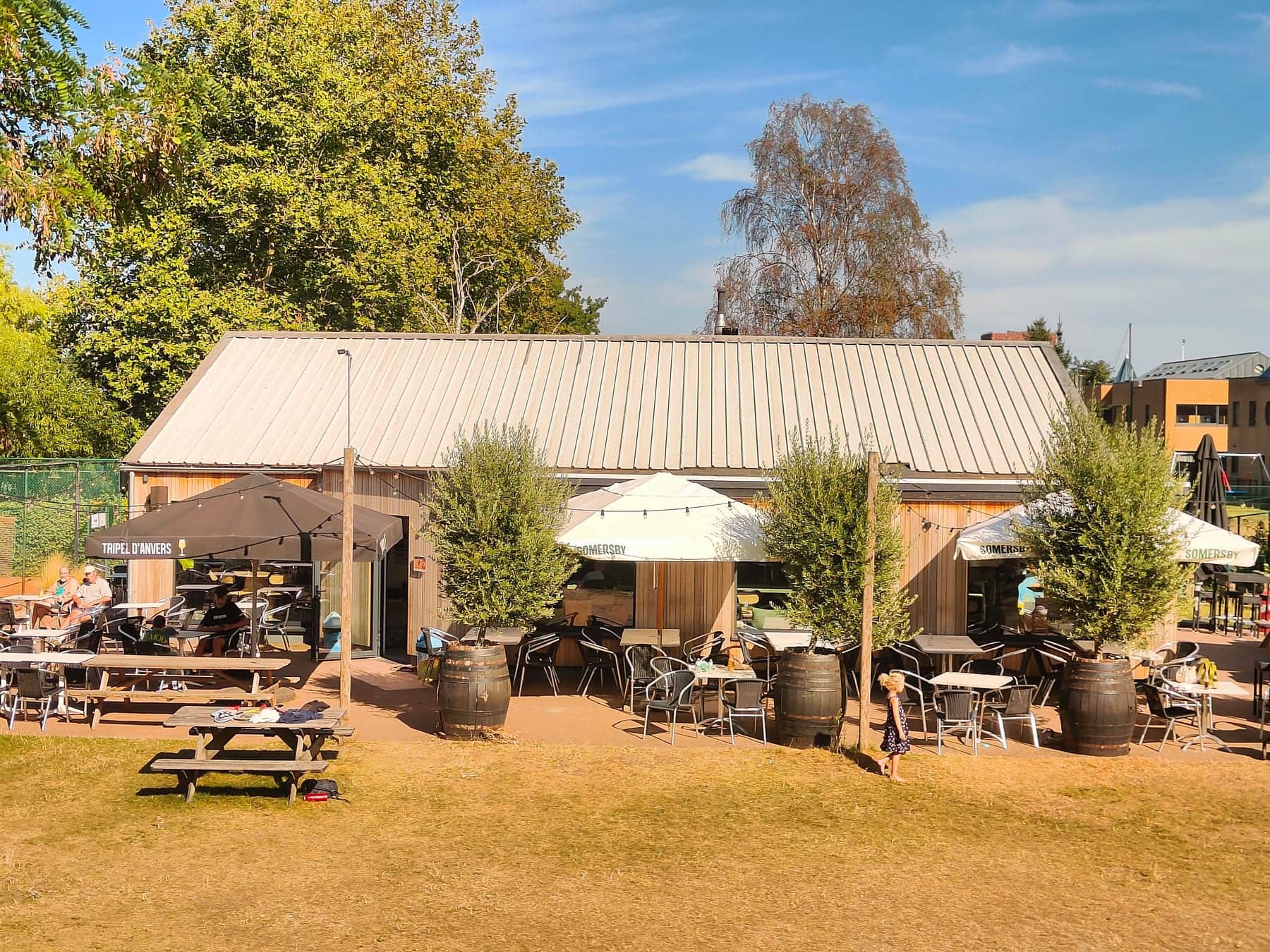Het terras langs het houten clubhuis, met tafels en plantvakken